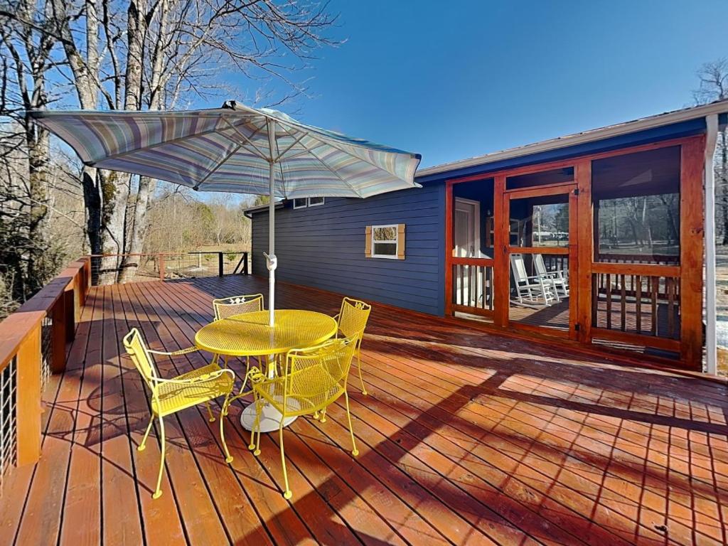 a wooden deck with a table and chairs and an umbrella at Caney Creek in Jenkins Mill