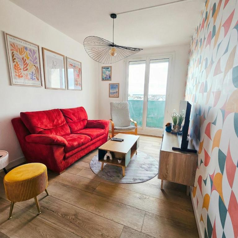 a living room with a red couch and a table at L'Atelier Eiffel Moderne & confortable in Saint-Brieuc