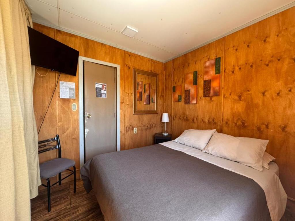 a bedroom with a bed and a chair at Hotel de la Costa in Talcahuano
