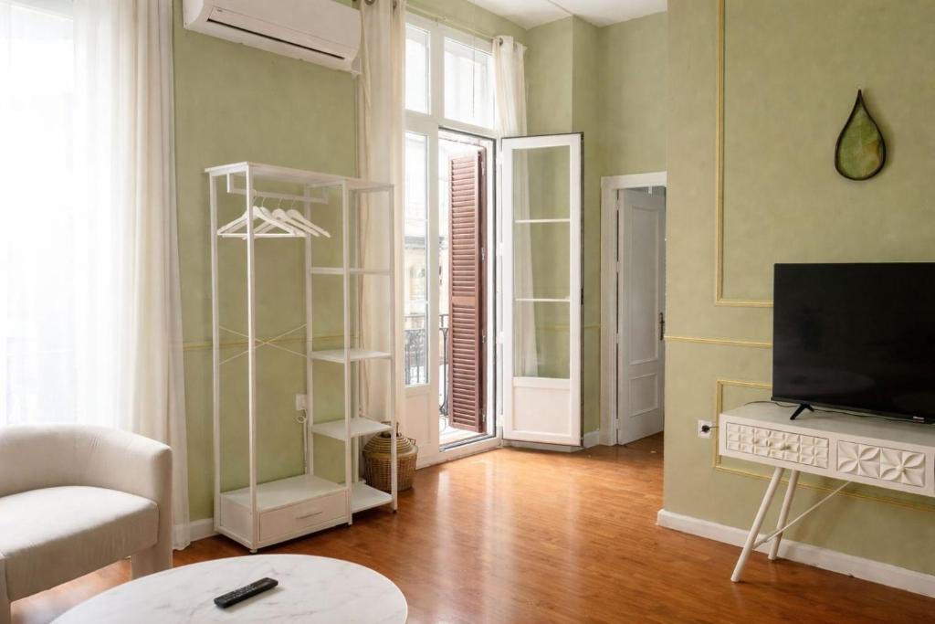 a living room with a tv and a couch and a table at Apartamentos Málaga centro in Málaga