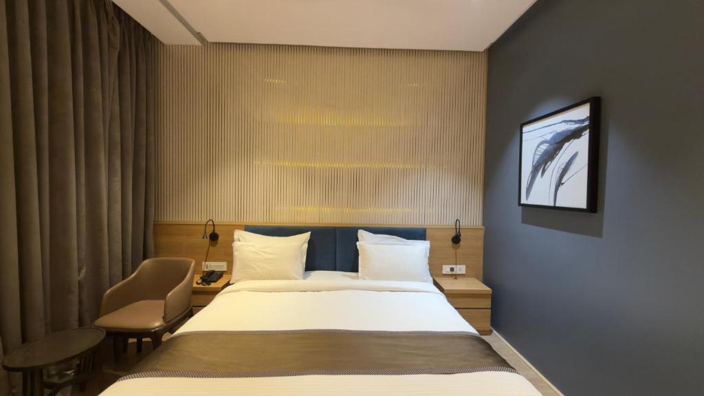 a hotel room with a bed and a chair at Kratos Lifestyle in Surat
