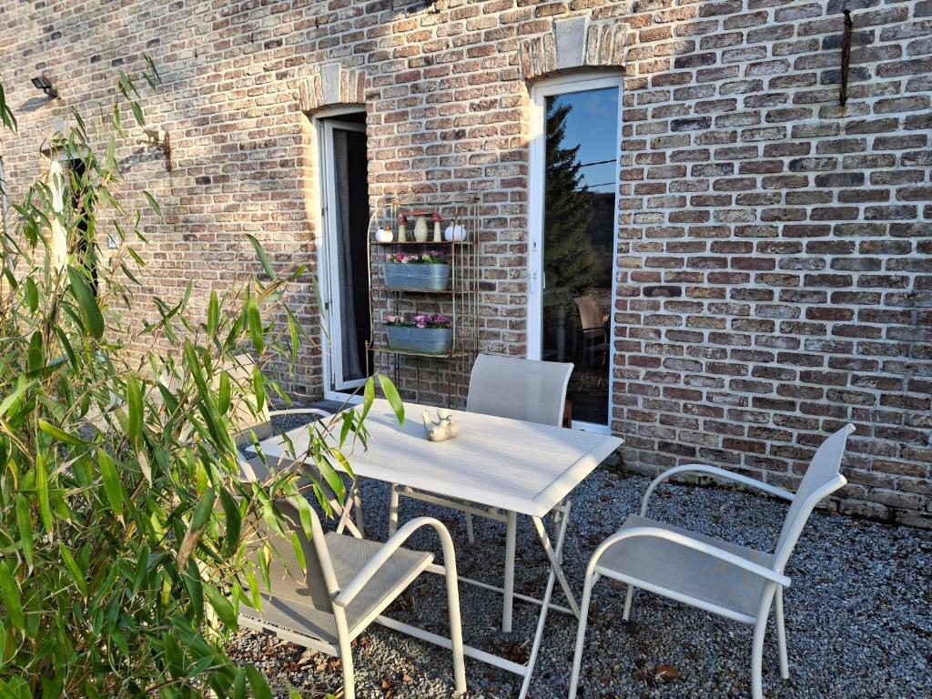 a white table and chairs and a brick wall at La Maison des Senteurs in Francorchamps