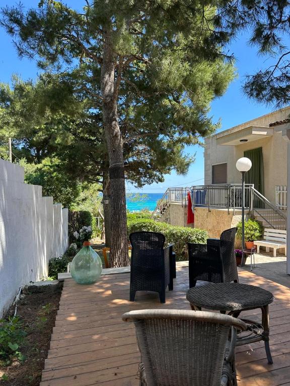a patio with chairs and a table and a tree at Casa Punta d'Oro in Faccia di Trippa