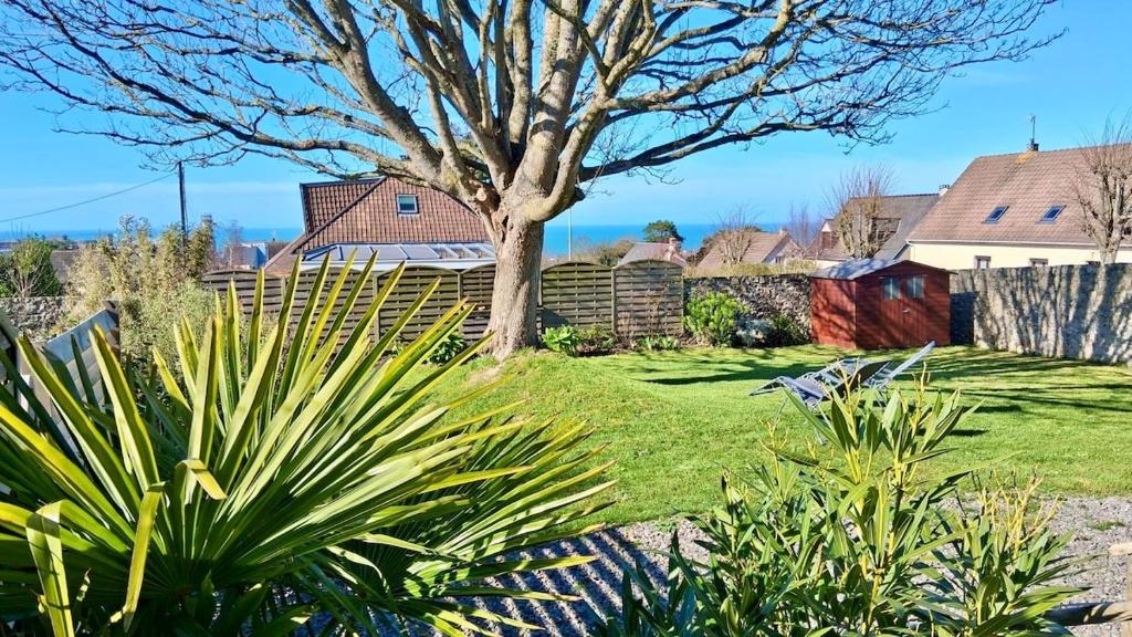 a yard with a tree and some plants at L'Erable - Maison vue mer in Donville-les-Bains
