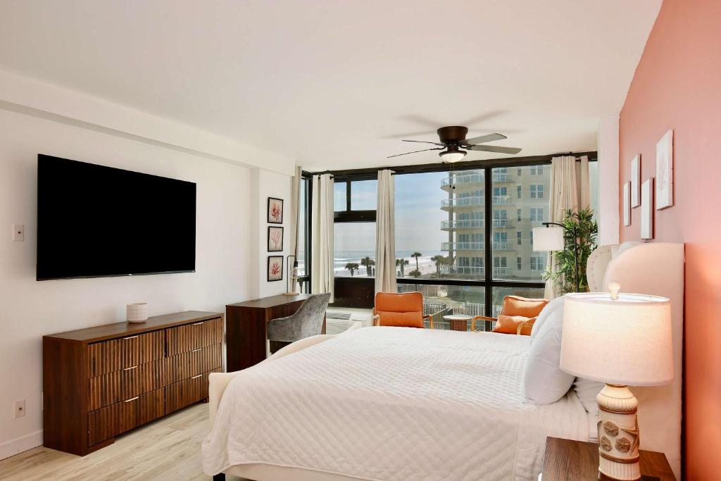 a bedroom with a bed and a flat screen tv at Beach Studio with Partial Water Views Sundeck Pool in Daytona Beach