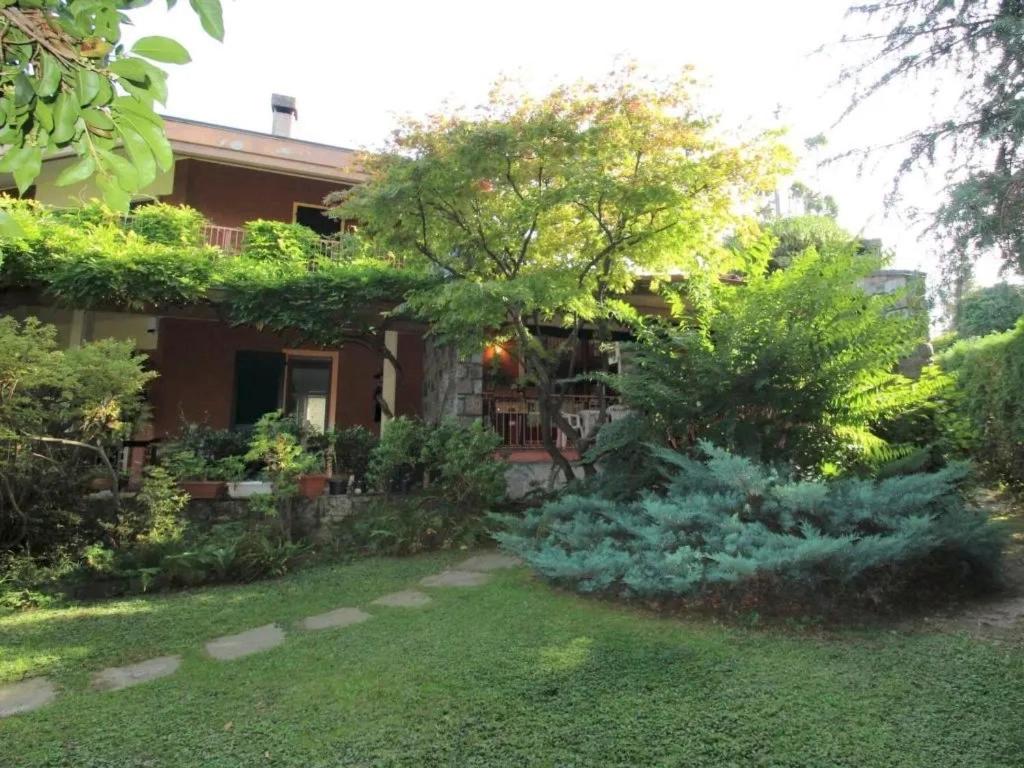 a garden in front of a house at Parco Hermitage - Villa Azalea in Porto Valtravaglia