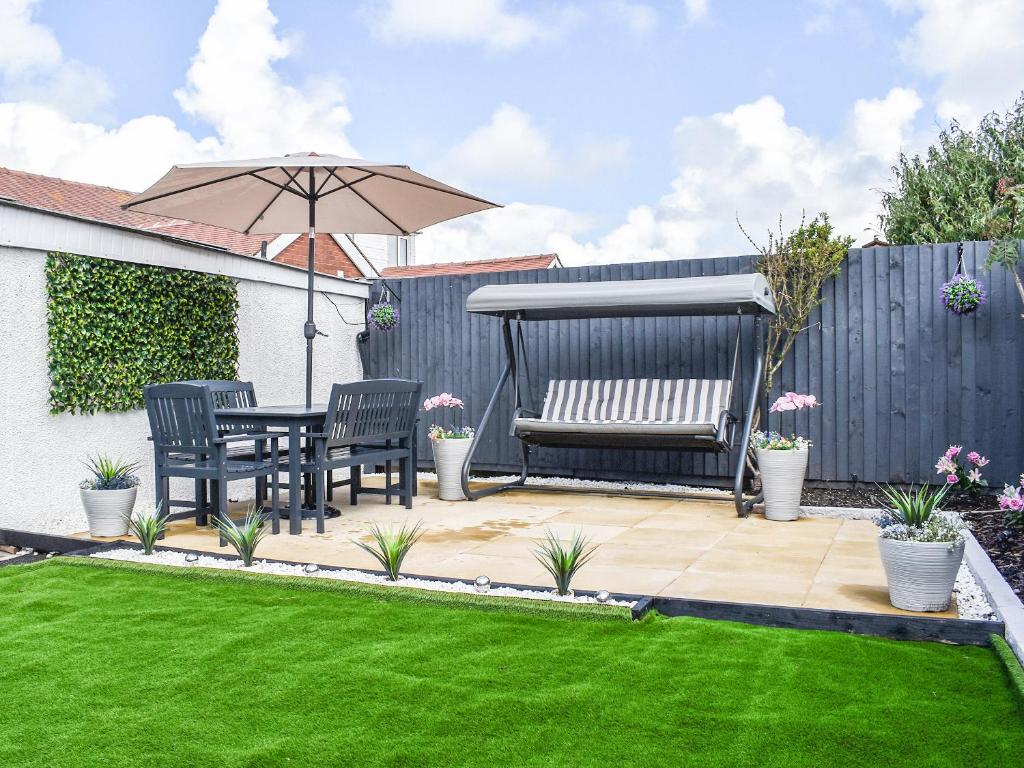 a patio with a table and a bench and an umbrella at Newcastle Lodge in Thornton