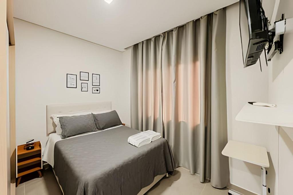 a small bedroom with a bed and a television at Alto padrão, 2 suítes e lazer privativo in Joinville