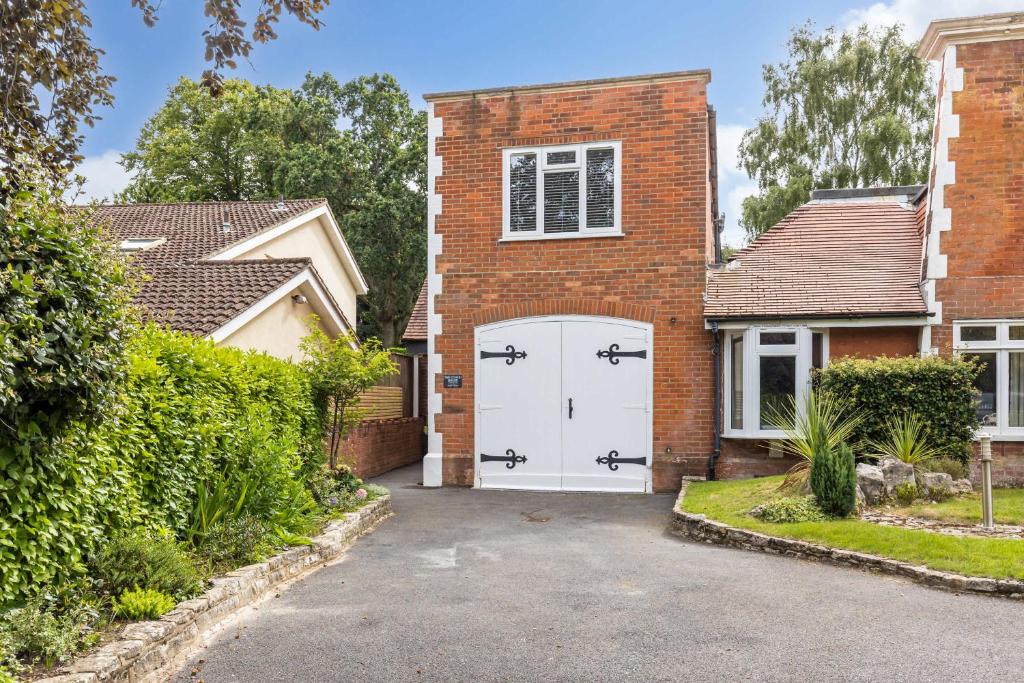 a brick house with a white garage at Middle Chine - Beautiful Garden and Spacious Living Space in Bournemouth