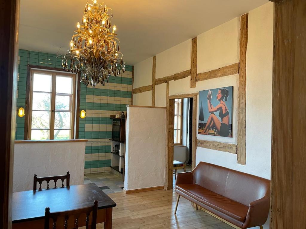 a living room with a couch and a table and a chandelier at Der Schwan - Gutshaus Bückling in Rambin