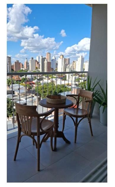 a table and chairs on a balcony with a view of a city at Departamento equipado en el macrocentro santa fe in Santa Fe