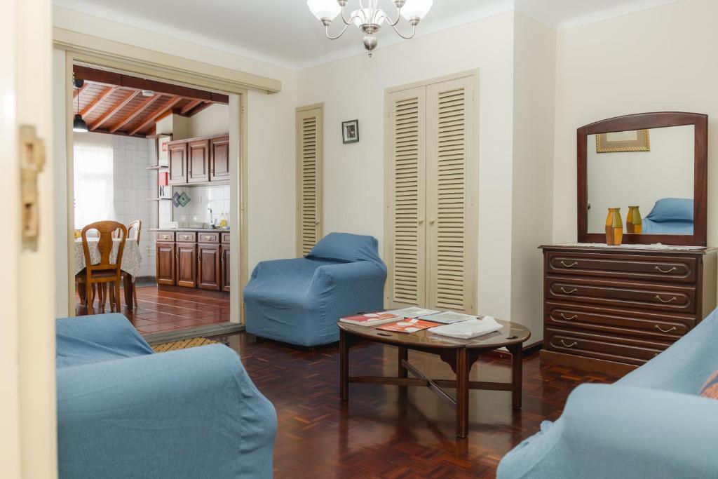 a living room with a blue couch and a table at Northern Breeze Comfort in Ribeira Grande