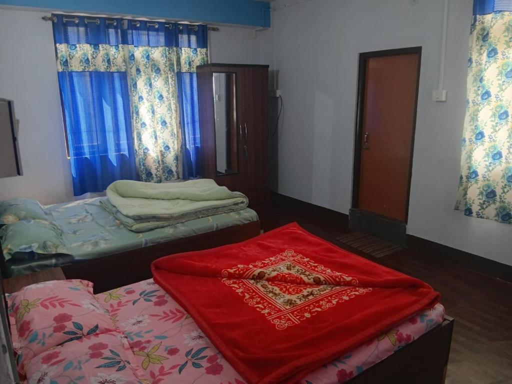 a room with two beds and a red blanket at Aashirwad homestay in Aritar