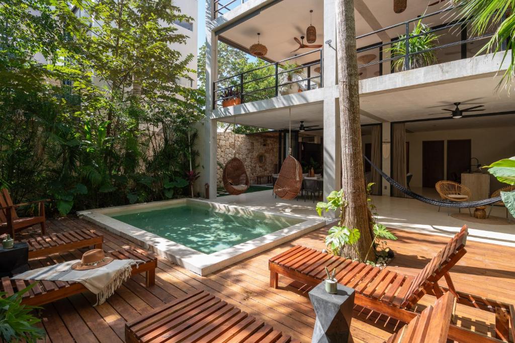 a pool on a deck with chairs and a house at Limas in Tulum