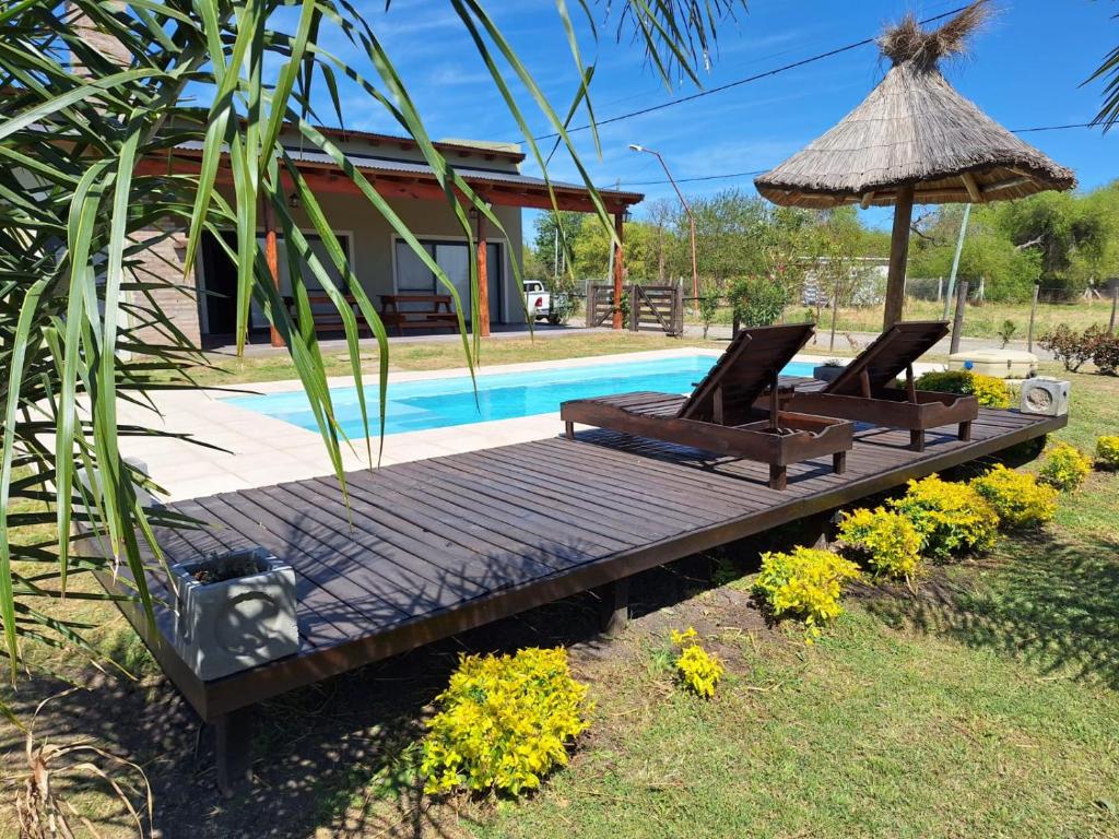 a deck with two chairs and an umbrella next to a pool at Quinta El Oasis ORO VERDE in Oro Verde