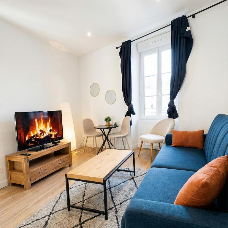 a living room with a blue couch and a fireplace at L'Entre Deux Gare Centre-Ville in Saint-Brieuc