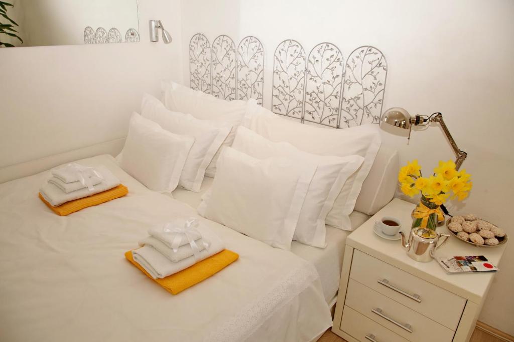 a room with a bed with white sheets and towels at Apartment Spacious Liman in Novi Sad