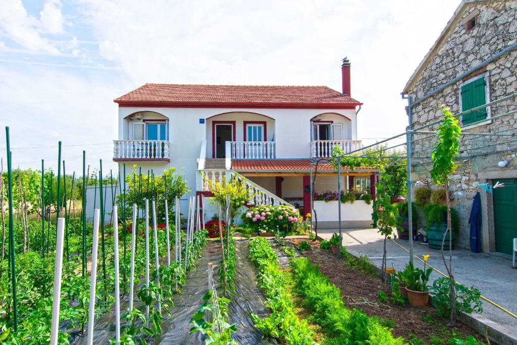 a house with a garden in front of it at Apartments Miljenko in Dobropoljana