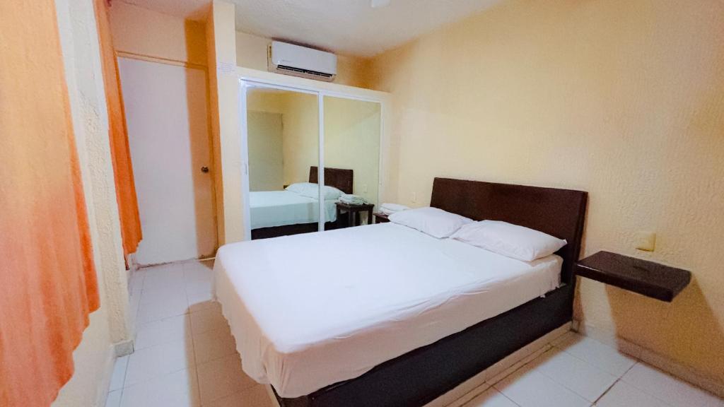 a bedroom with a white bed with a mirror at HOTEL PARAISO ACAPULCO in Acapulco