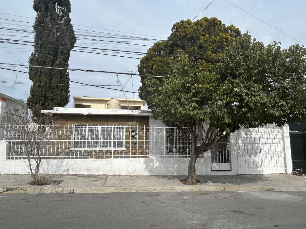 a white fence with a tree in front of a house at Se Renta Casa in Saltillo