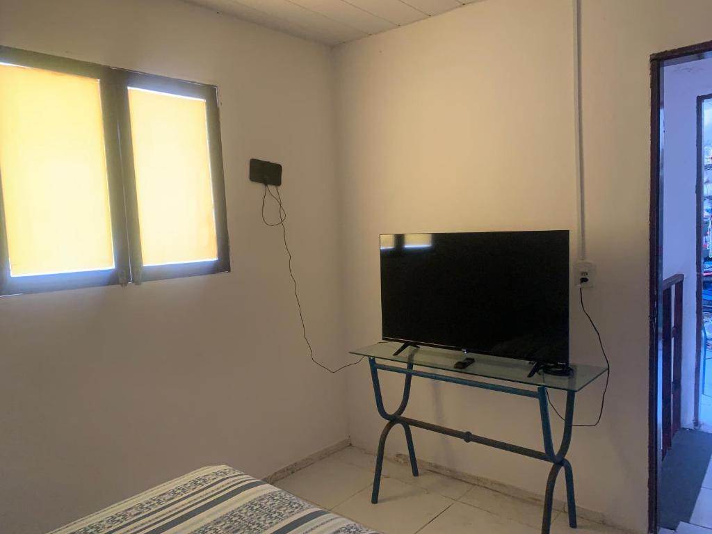 a television on a table in a room with a bed at casa aconchegante proximo a praia in Maceió