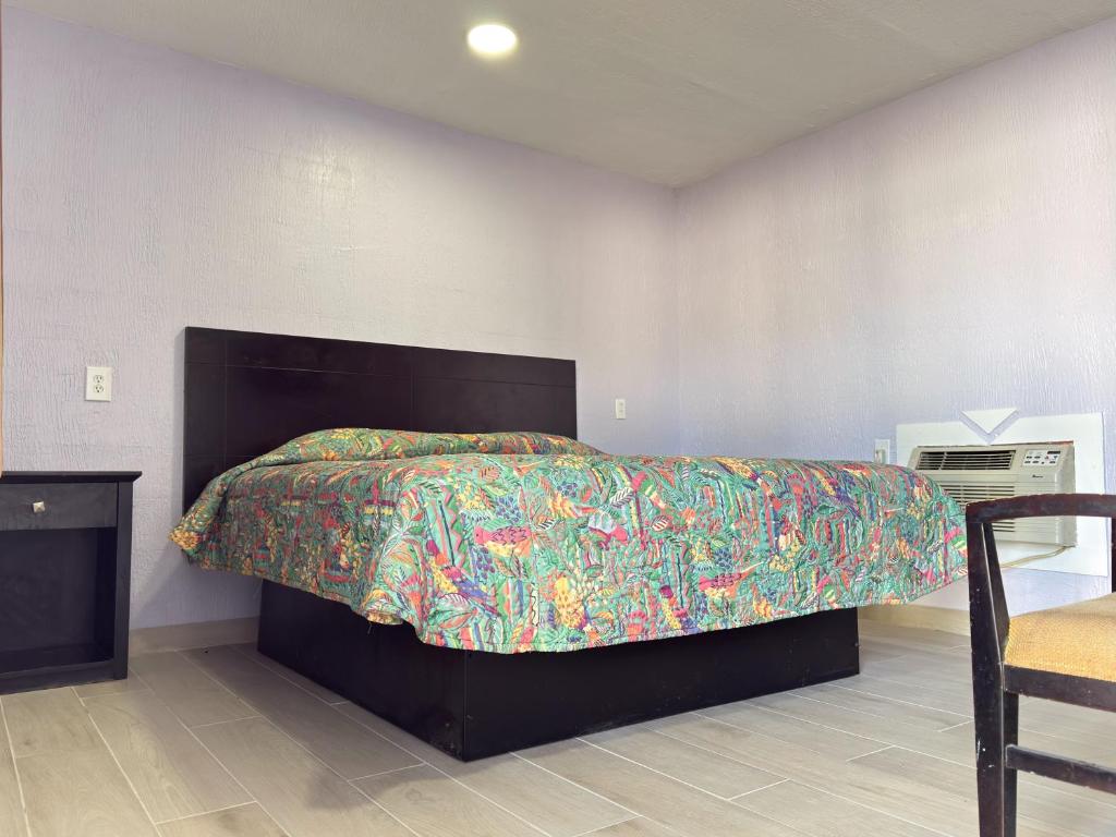 a bedroom with a large bed with a colorful bedspread at Vanguard Motel in Ormond Beach