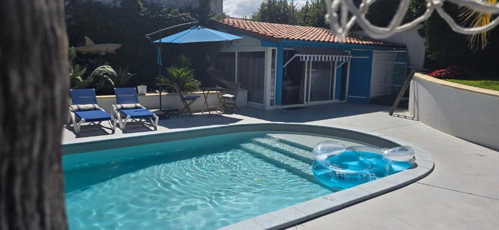 a swimming pool with a blue raft in a yard at Studio proche de l'Océan - Calme et Pratique in Capbreton