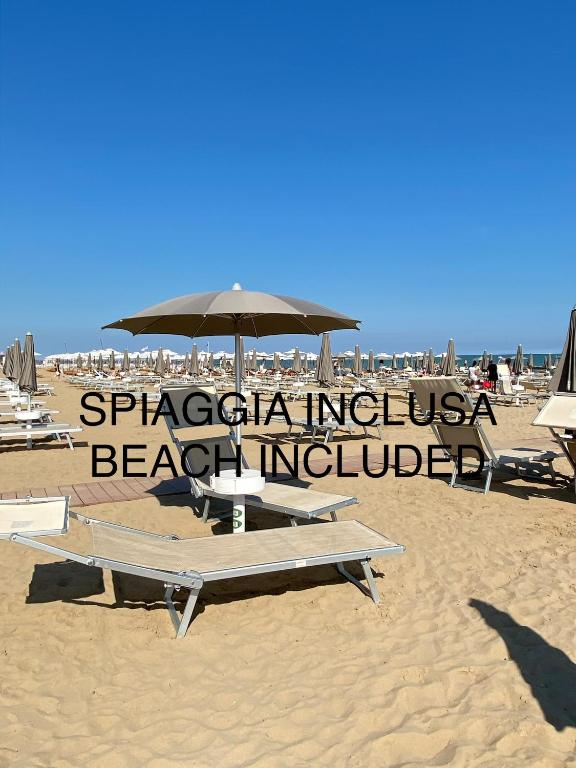 a beach with chairs and an umbrella on the sand at Hotel Storione in Lido di Jesolo