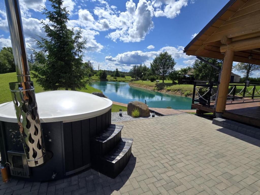 a hot tub on a patio with a view of a river at Vila Noruciai in Šašeliai