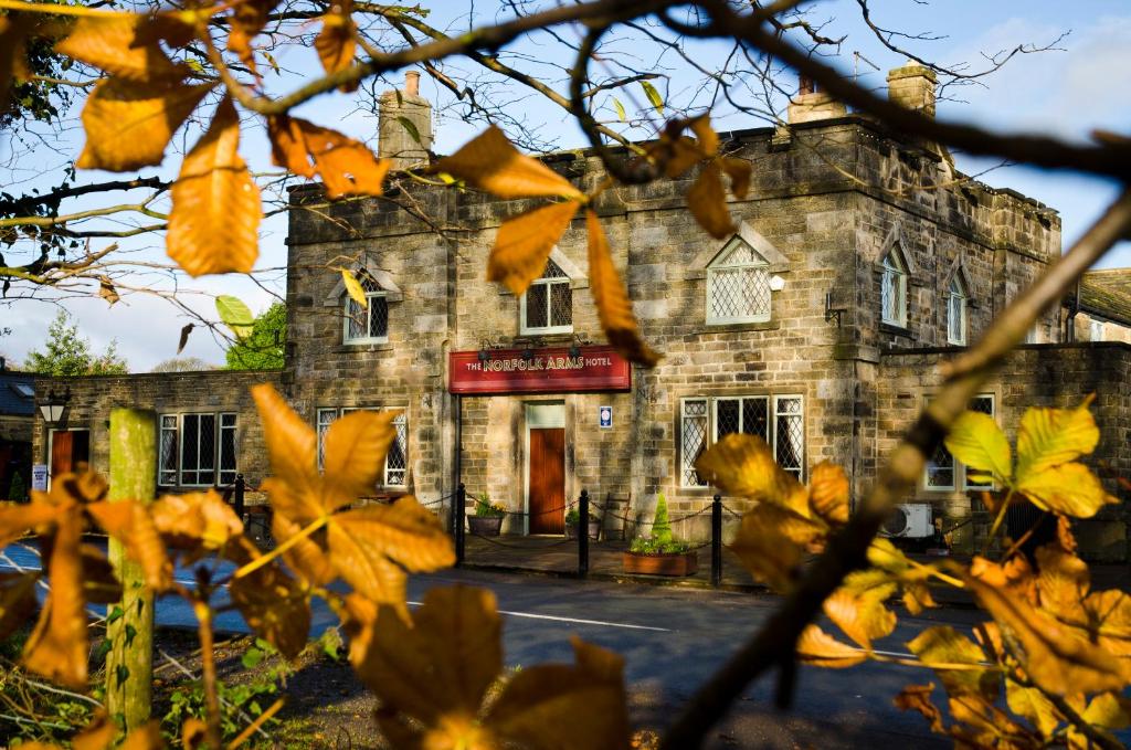 un viejo edificio de piedra es visto a través de un árbol en Norfolk Arms Hotel, Ringinglow, en Sheffield