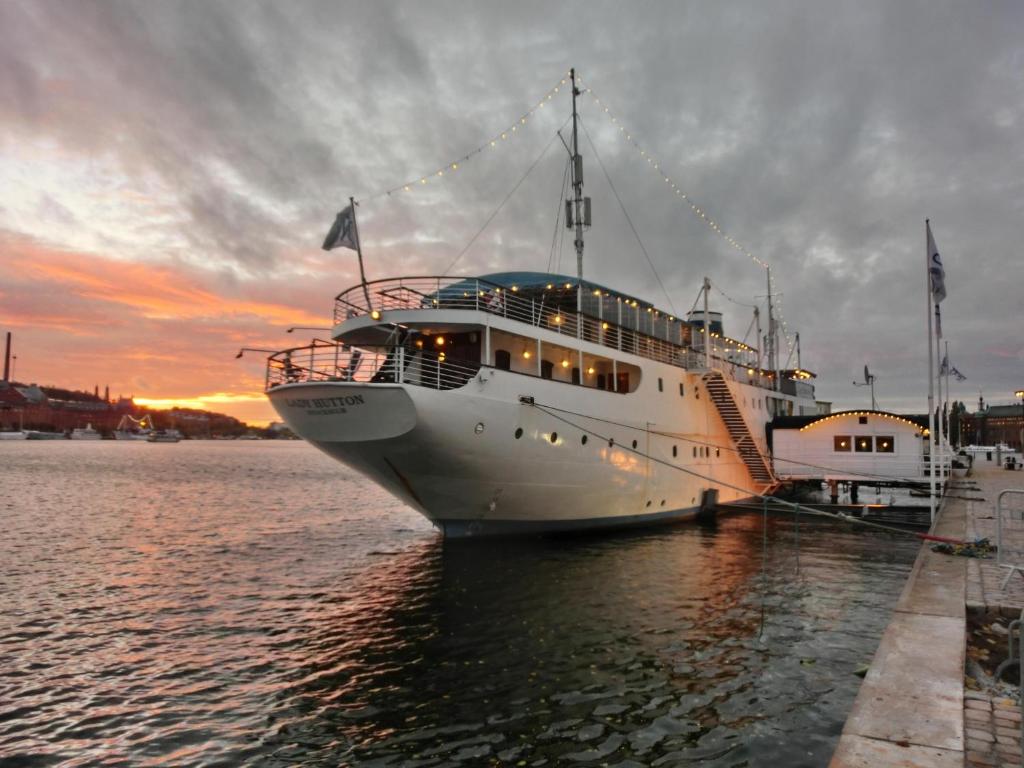 um navio de cruzeiro está ancorado na água ao pôr-do-sol em Mälardrottningen Yacht Hotel em Estocolmo