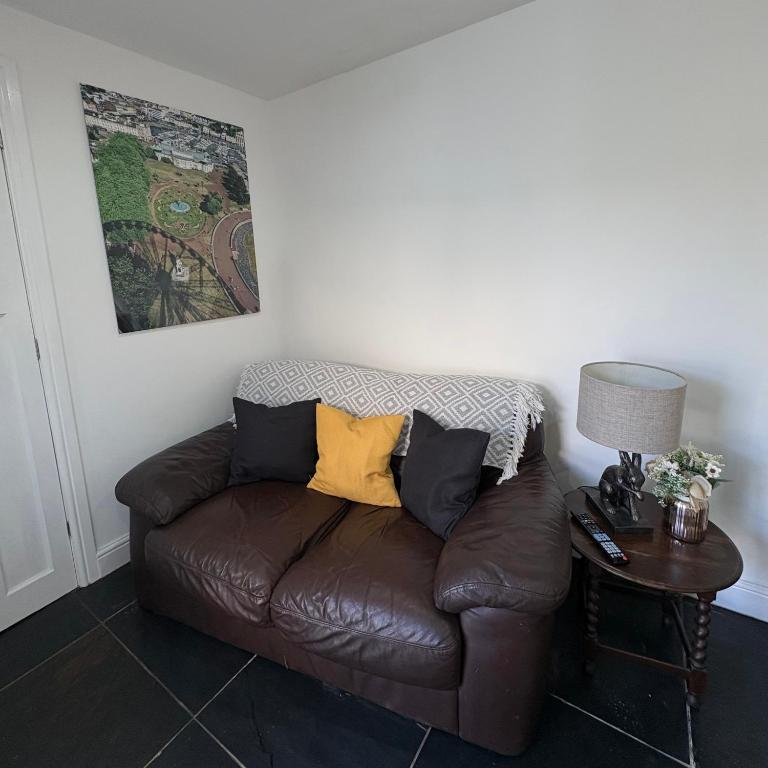 a brown leather couch with two yellow pillows on it at Santa's Cottage in Torquay