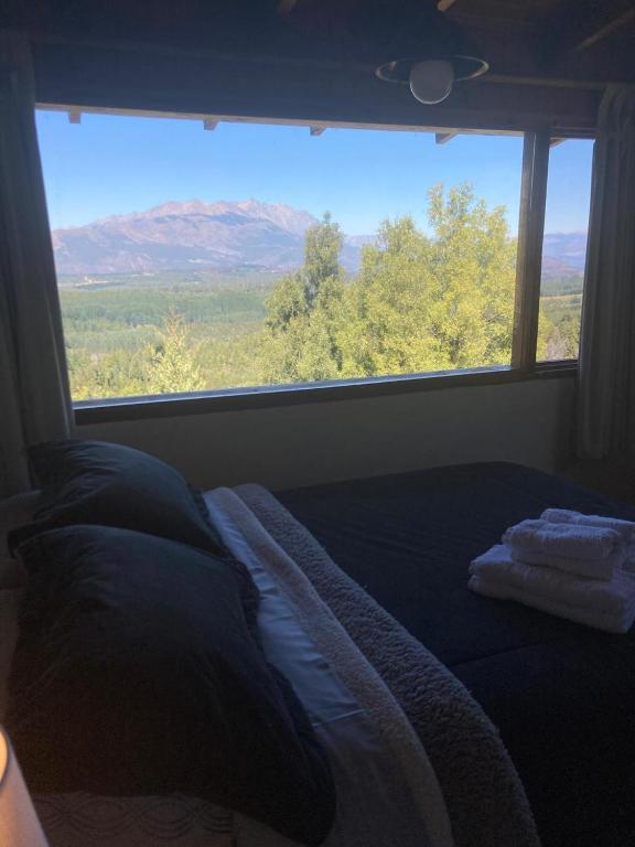 a bed in a room with a large window at Las Morillas in El Bolsón
