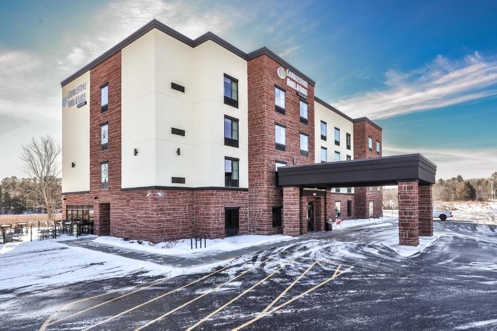 a large brick building with snow on the ground at Cobblestone Hotel & Suites - Monte Vista in Monte Vista