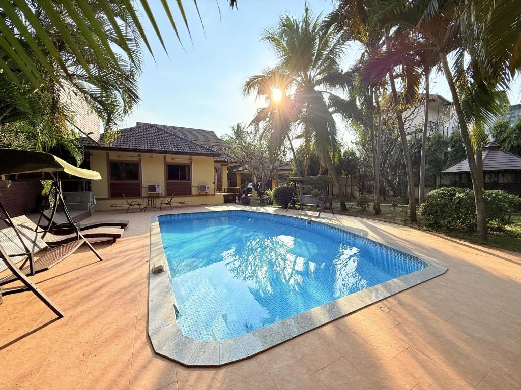 a swimming pool in front of a house with palm trees at Yellow House Garden Pool Villa in Chiang Mai