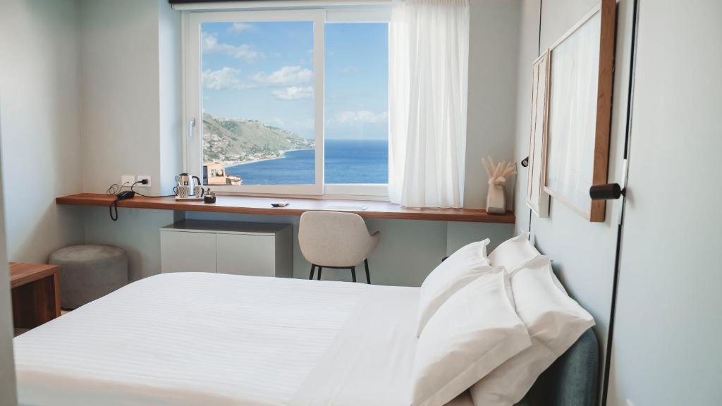 a bedroom with a bed and a desk and a window at TPH Rooms in Taormina