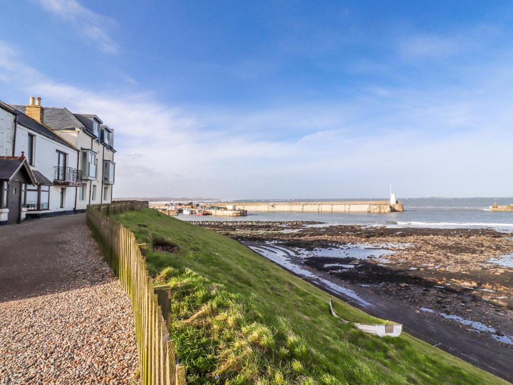 a house on the beach with a pier in the background at Cuddy's Holm in Seahouses