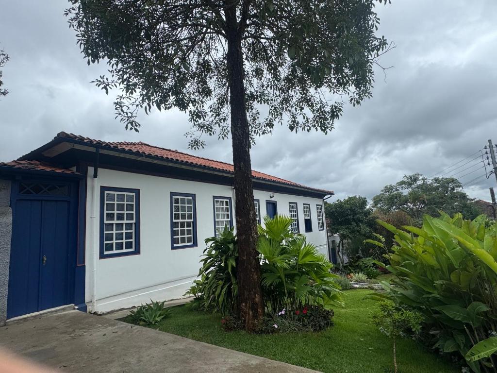 a small house with a blue door and a tree at Casa da Glória 1 in Diamantina