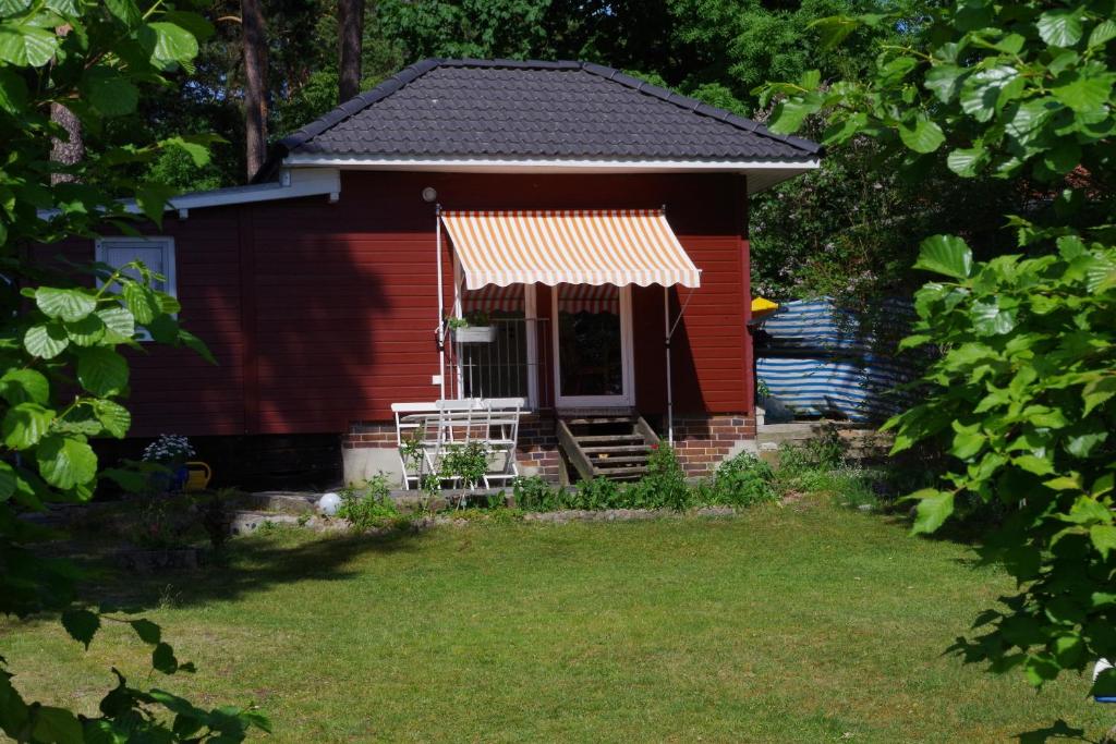 ein rotes Haus mit einer Veranda und einem Stuhl im Hof in der Unterkunft Haus Silke am See in Groß Köris