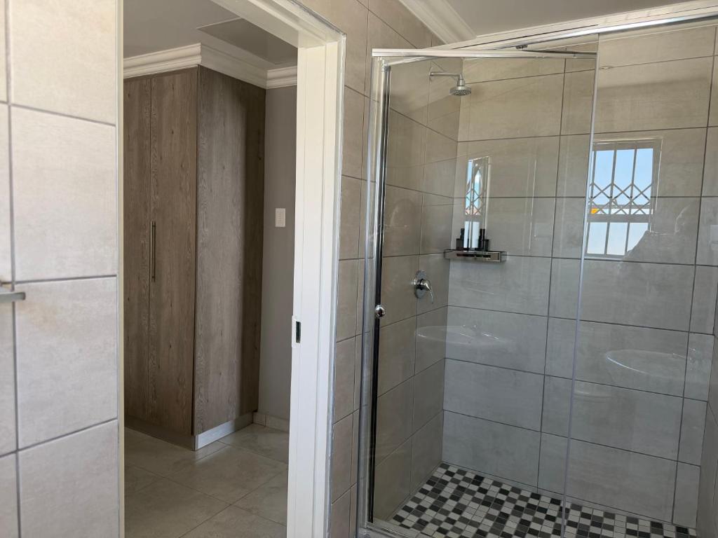 a shower with a glass door in a bathroom at Saviour Apartments in Mthatha