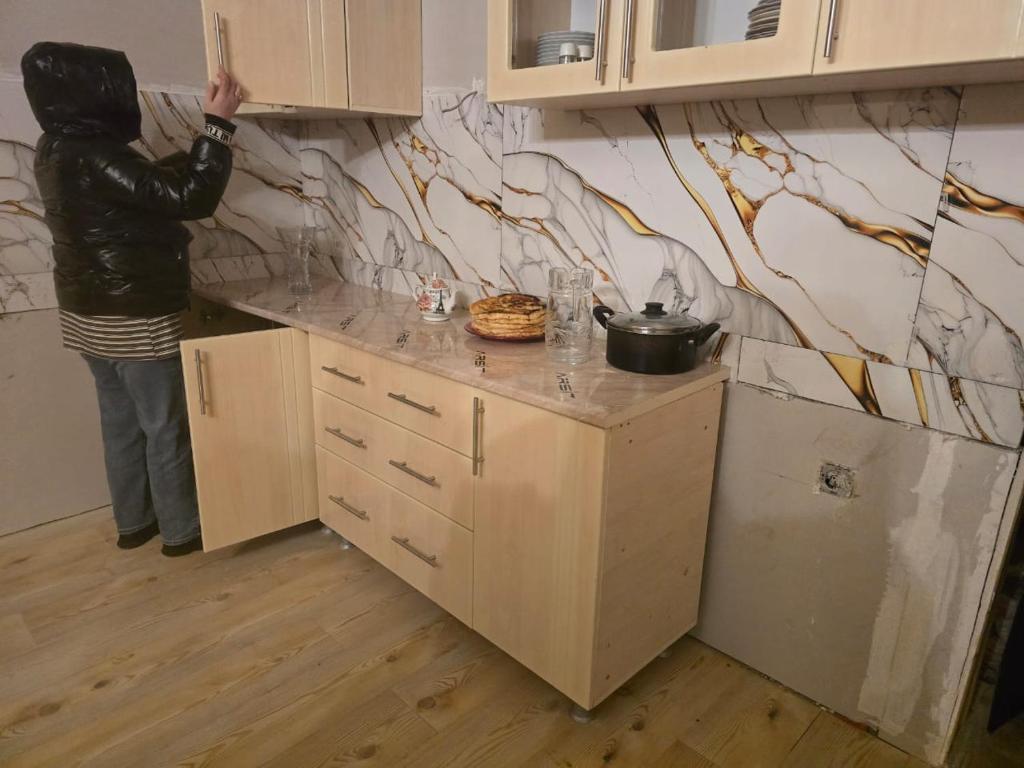 Eine Person steht in einer Küche und malt eine Wand. in der Unterkunft goderdzi apartaments in Danisparauli