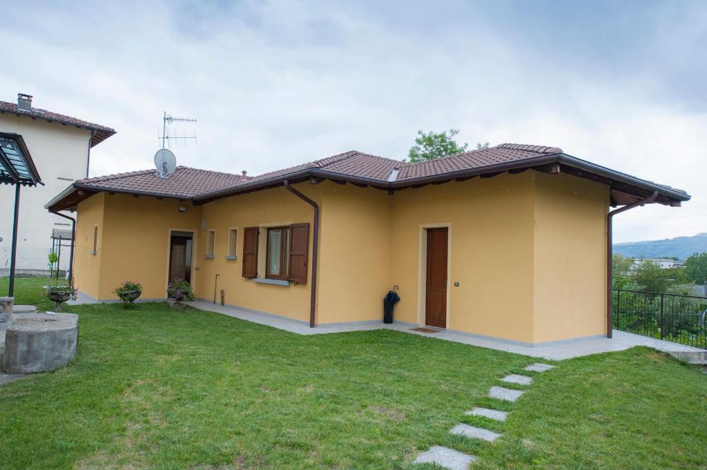 a small yellow house with a lawn in front of it at villetta a schiera in Intra