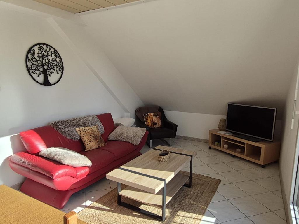 a living room with a red couch and a tv at maison prairie in Haguenau