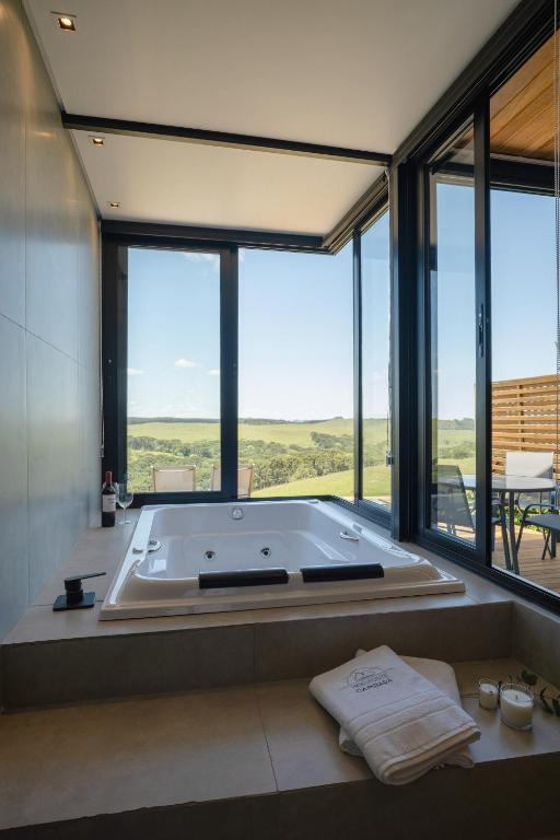 a large bath tub in a room with large windows at Cabanas Horizonte Cambará Solare in Cambará
