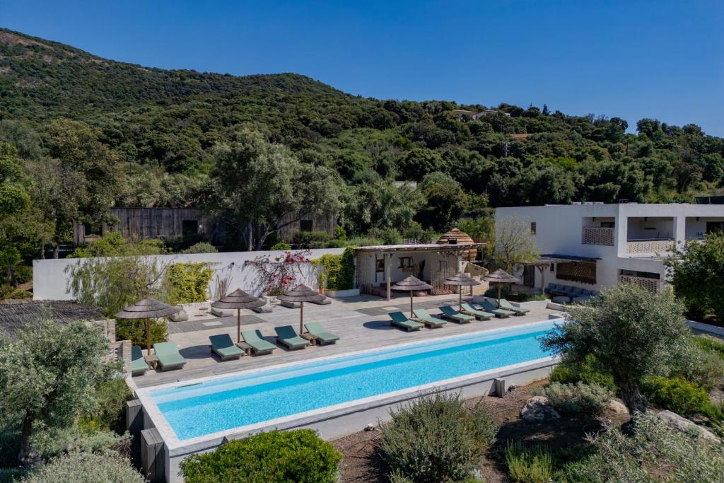 a pool with chairs and umbrellas next to a building at VILLA FLAKA Boutique Hôtel Wellness in Cargèse