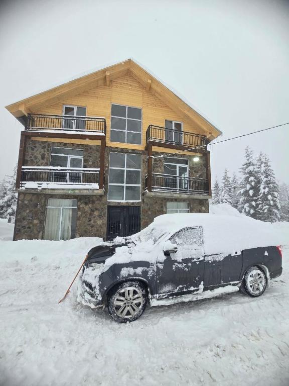 a car covered in snow in front of a house at goderdzi booking in Goderdzi