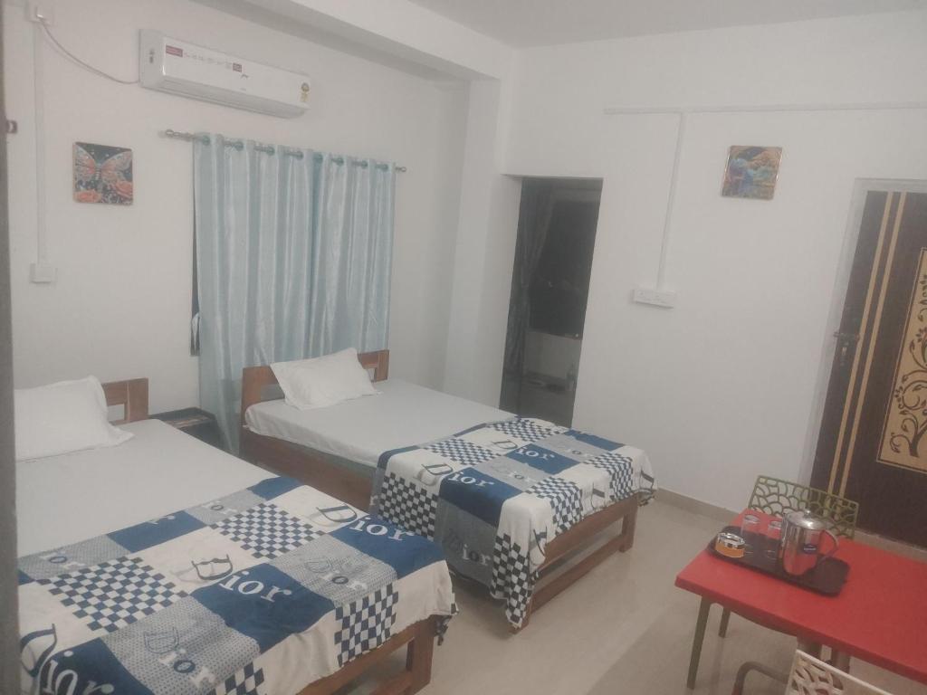 a room with two beds and a red table at Morisika lodge in Guwahati
