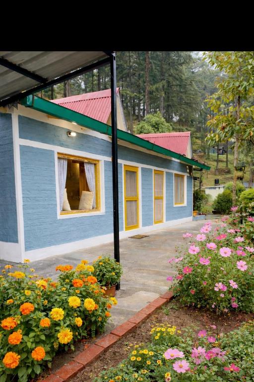 a small blue house with flowers in front of it at Peak & Pine cottage in Almora