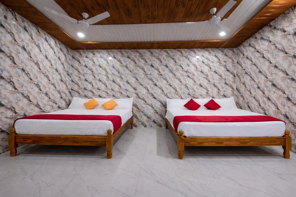 two beds with red and orange pillows in a room at Lakshmi Divya Guest house in Pedda Ahobilam