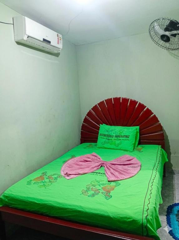 a bedroom with a bed with a green comforter at Quarto de Pousada in Imperatriz